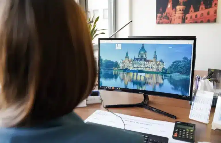 Frau blickt auf Computerbildschirm mit geöffnetem Website-Design der Stadt Hannover
