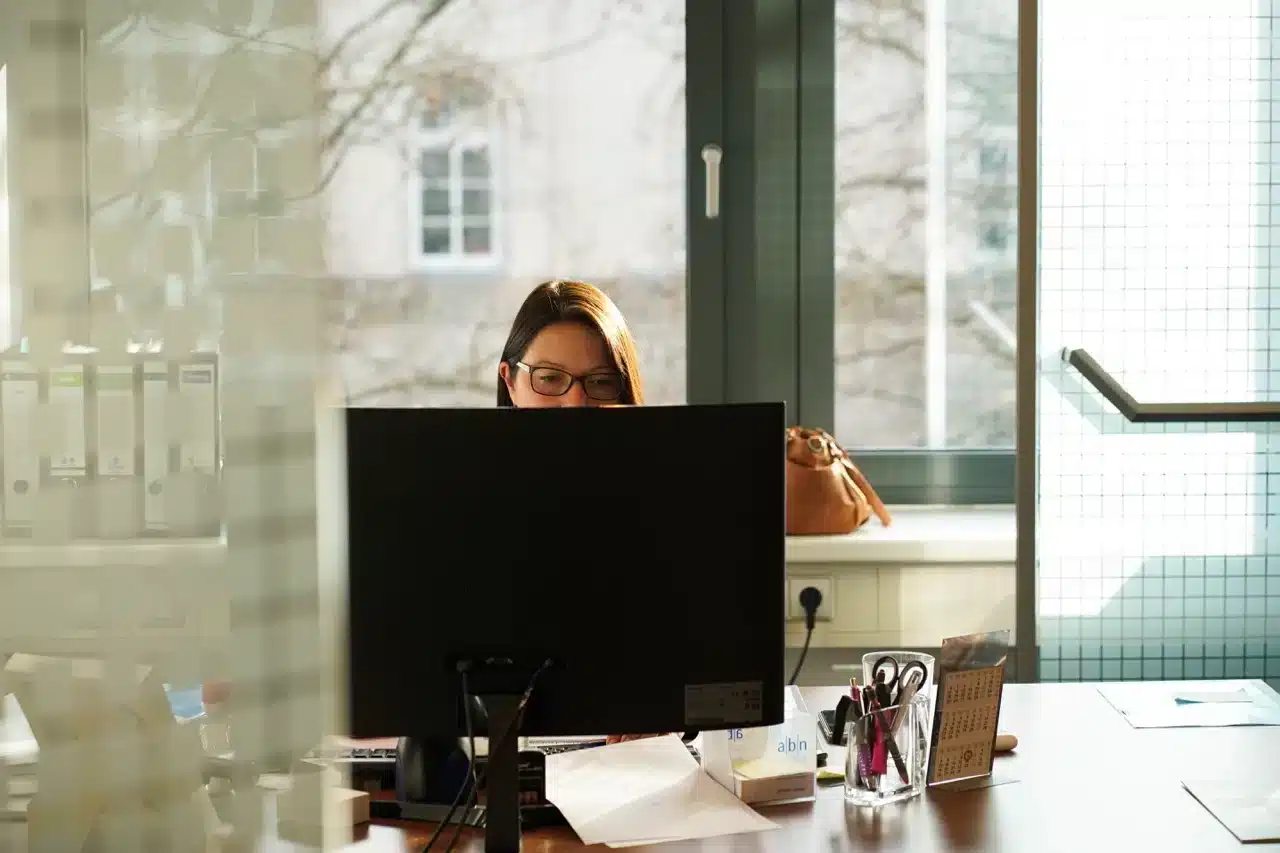personalueberlassung-abn-hannover Frau arbeitet konzentriert am Schreibtisch im Büro bei Tageslicht